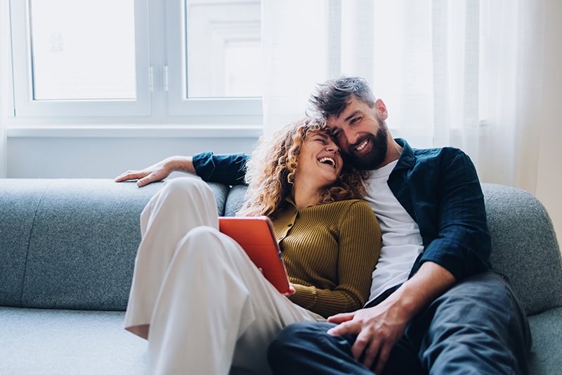 A couple happily sitting on the couch.